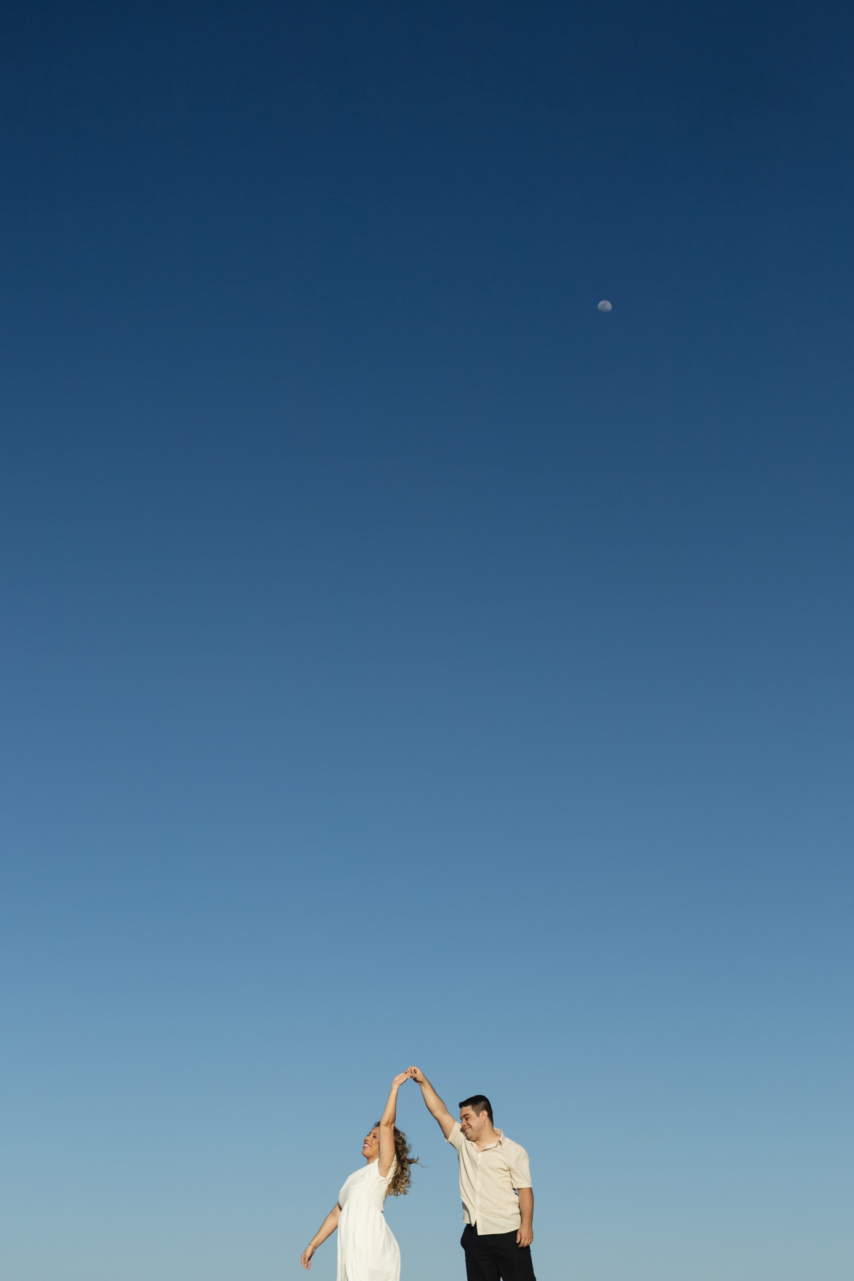 John e Larissa dançando sob o céu azul
